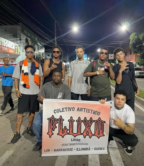 O Coletivo Fluxo Livre reunido na rua à noite, segurando a faixa do coletivo